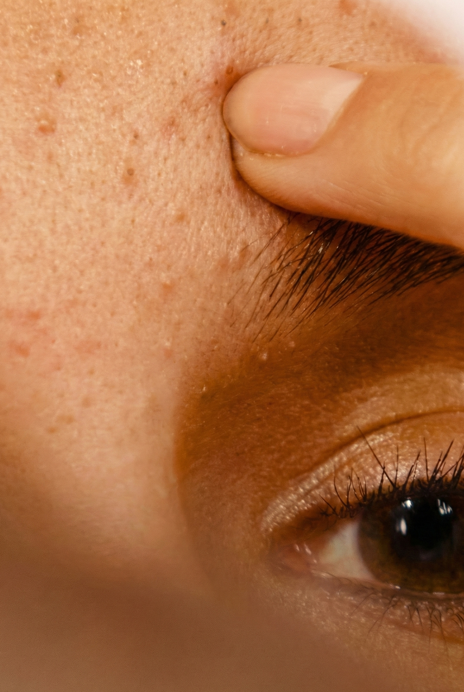 Close-up of a person's eye with a finger on the brow